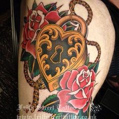 a heart shaped lock and roses tattoo on the thigh