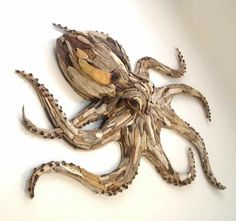 an octopus sculpture made out of driftwood on a white wall in the shape of a human head