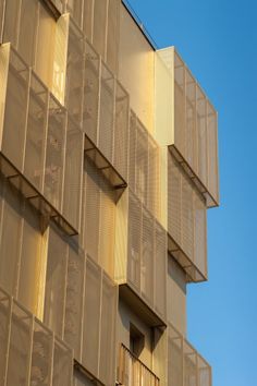 a tall building with lots of windows and balconies on the top floor, in front of a blue sky