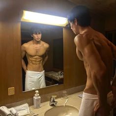 a shirtless man standing in front of a bathroom mirror looking at himself in the mirror