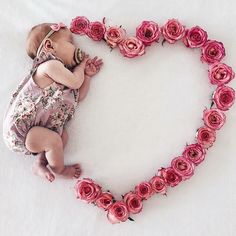 a baby is laying in the shape of a heart with roses on it's side