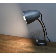 a desk lamp sitting on top of a wooden table next to a white wall and floor