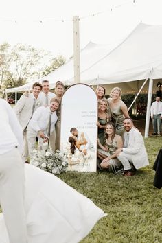 a group of people posing for a photo in front of a white sign and tent