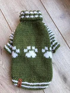 a green and white knitted dog sweater laying on the floor