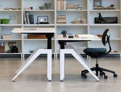 an office desk with two chairs in front of it and shelves behind the desk on either side