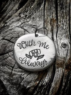 a metal keychain that says with me always on it sitting on a piece of wood