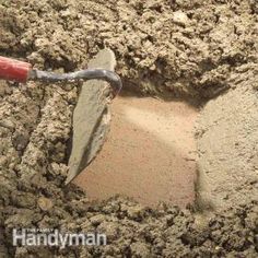 a shovel digging in the ground with dirt around it and a red handle on top