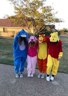 three children in winnie the pooh costumes standing next to each other on a sidewalk