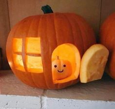 a pumpkin carved to look like a house with a window and smiling face on it