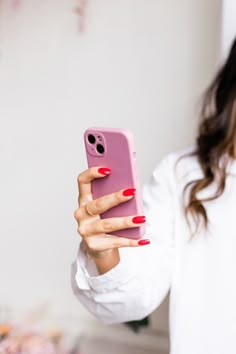 a woman taking a selfie with her cell phone in her hand while wearing red nail polish