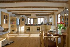 an open kitchen and dining room with wood flooring, white walls and beams in the ceiling