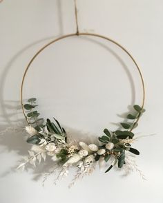 a wreath with white flowers and greenery is hanging on the side of a wall