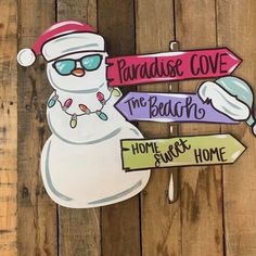 a wooden sign with snowman wearing sunglasses and santa hat