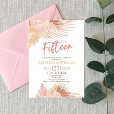 a pink and gold tropical themed wedding suite on top of an envelope with greenery