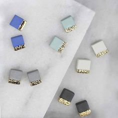 five different colored square shaped studs laying on top of a piece of white paper