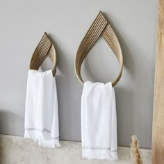 two white towels hanging on the wall next to a towel rack with wooden handles and hooks