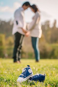 two people standing in the grass with their feet on each other and one person wearing blue shoes