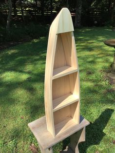 a wooden boat shaped shelf sitting in the grass