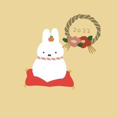 a white rabbit sitting on top of a red pillow next to a wreath with flowers