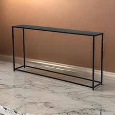 a marble table with a black metal frame on the top, in front of a brown wall