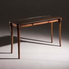 a wooden table sitting on top of a white floor next to a black wall with a shadow