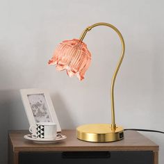 a table with a lamp on top of it next to a coffee cup and photo frame