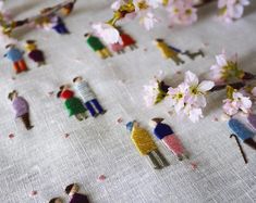 small figurines are placed on a tablecloth with pink flowers and tiny people