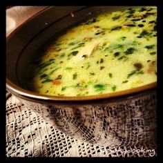 a bowl filled with broccoli and cheese on top of a lace table cloth