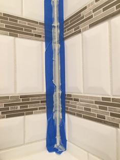 a white tub with some blue tape on the wall and tile in the bathtub