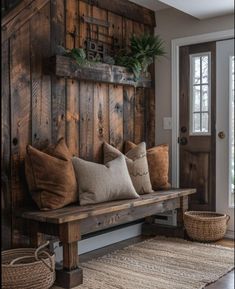 a wooden bench sitting in front of a door with pillows on top of it next to a rug