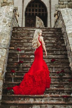 a woman in a red dress is walking down some stairs