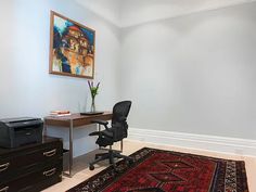 a room with a rug, computer desk and printer