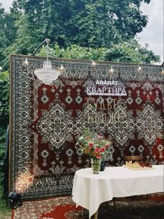 a table with flowers on it in front of a tapestry