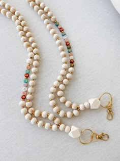 a white beaded necklace with gold clasps on a white tablecloth next to a pair of earrings