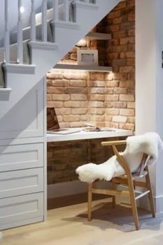 a white chair sitting under a stair case next to a desk with a computer on it