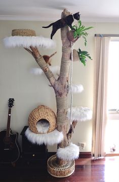 a cat climbing up the side of a tree in a living room next to a guitar