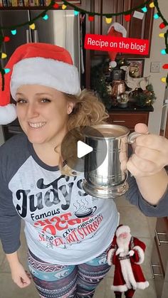 a woman in a santa hat is holding a silver pot and smiling at the camera