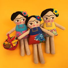 three wooden dolls are standing next to each other on a yellow background with a basket in the foreground