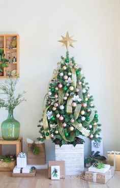 a decorated christmas tree in a living room next to boxes with presents under it and a star on top