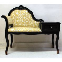 a black and yellow couch sitting on top of a wooden table next to a white wall