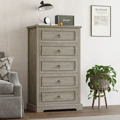 a grey chest of drawers in a living room next to a chair and potted plant