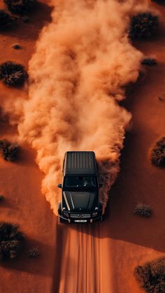 an suv driving through the desert with dust coming out of it