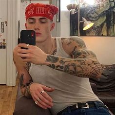 a tattooed man taking a selfie with his cell phone