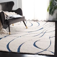 a white rug with blue swirls on it in a living room next to a chair