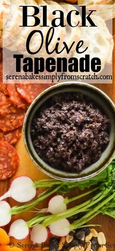 black olive tapenade in a bowl on a cutting board with sliced vegetables and bread