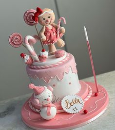 a pink and white cake with a girl holding a lollipop