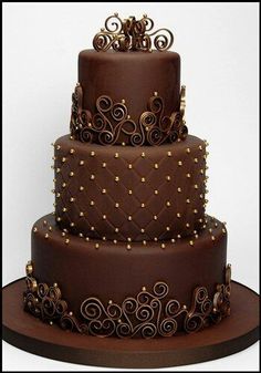 a three tiered chocolate cake with gold decorations