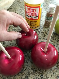 two apples being dipped with toothpicks on a counter