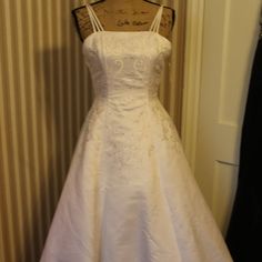 a white wedding dress hanging on a mannequin in a room with striped walls