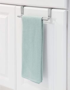 a green towel hanging on the side of a white kitchen cabinet with drawers and cupboards